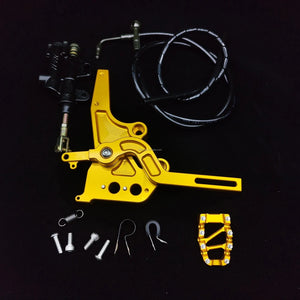 Gold Sur-Ron Light Bee foot-brake pedal assembly with master cylinder, hose, toe peg and hardware laid out for install