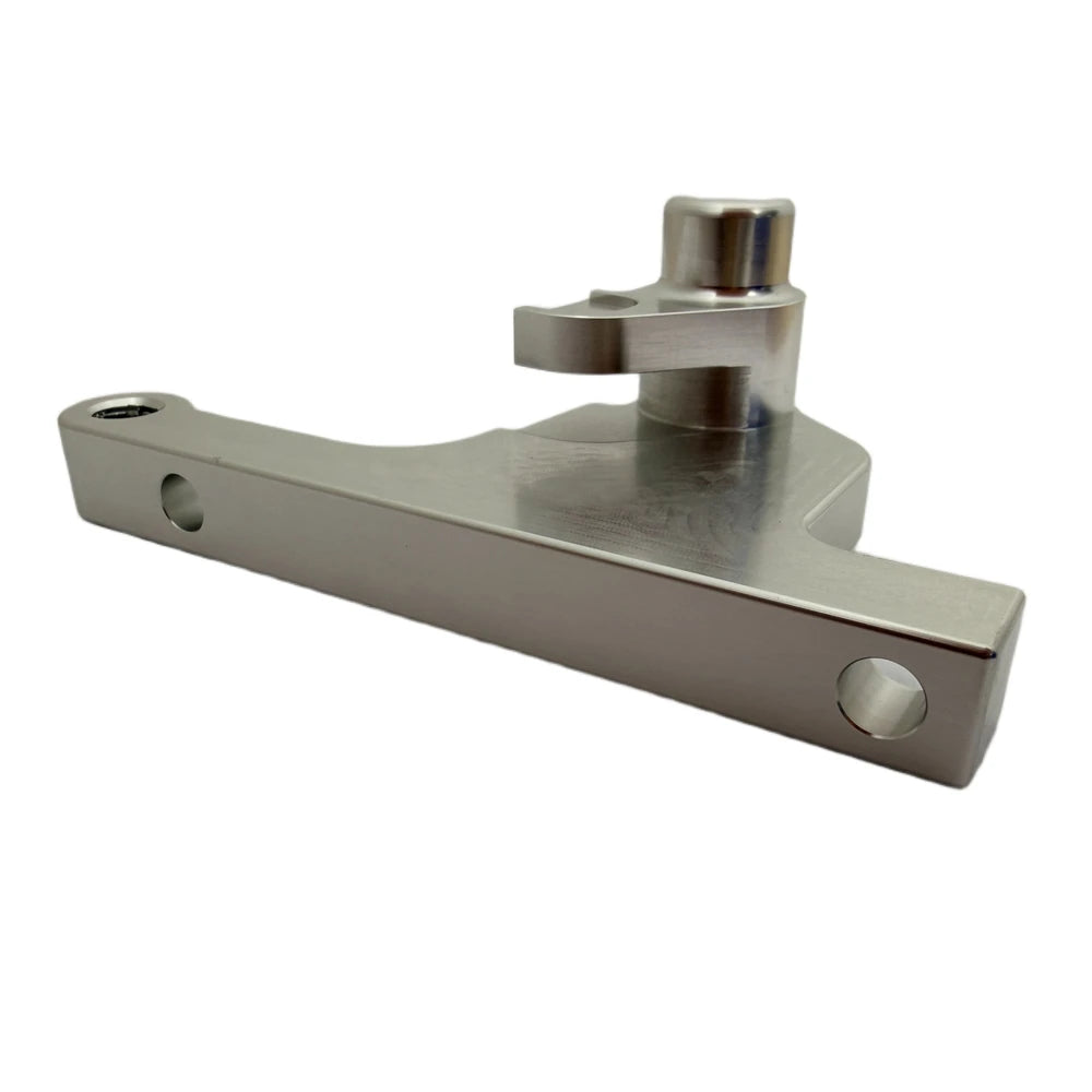 Surron CNC-machined front brake caliper bracket, raw silver aluminum finish, angled close-up showing mounting holes and caliper boss