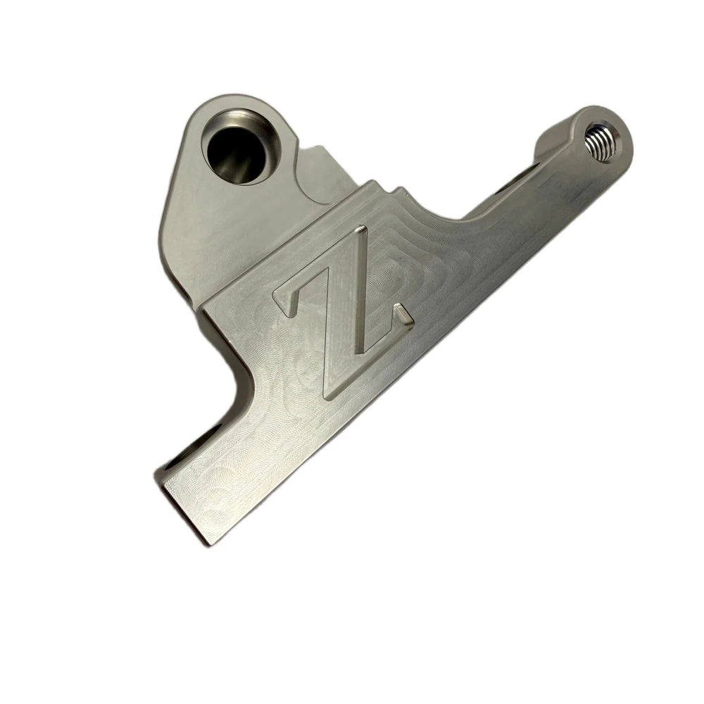 Surron front moto brake caliper bracket, CNC-machined silver aluminum with engraved FactoryZ Z logo, angled view
