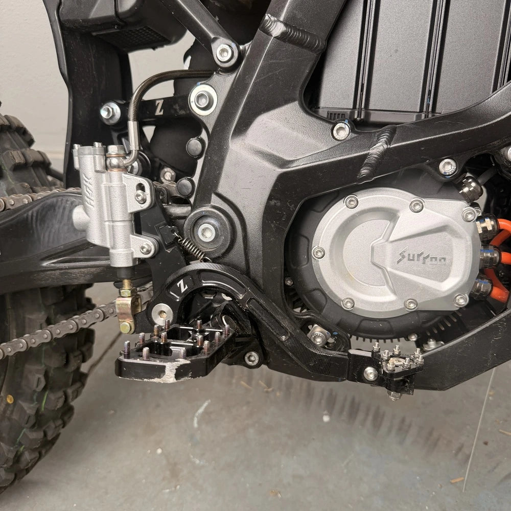 Surron Ultra Bee foot brake installed on the bike, silver HSK master cylinder, braided line, black lever and peg