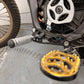 Talaria shift lock kit installed, black CNC-machined peg mount bracket with blue anodized bolts and silver foot peg