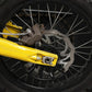 Surron Ultra Bee 240mm rotor installed on a rear wheel beside a bronze Nibbi caliper and yellow swingarm
