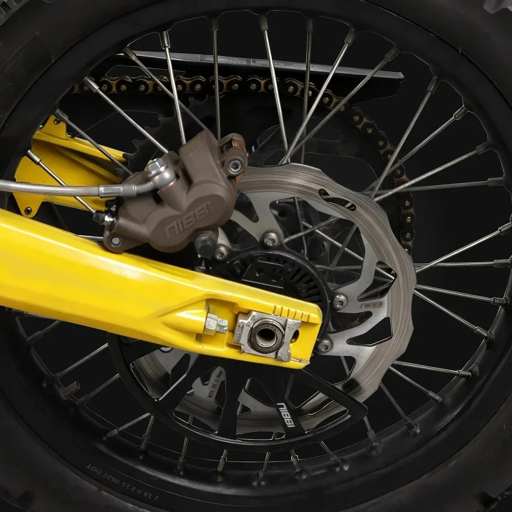 Surron Ultra Bee 240mm rotor installed on a rear wheel beside a bronze Nibbi caliper and yellow swingarm